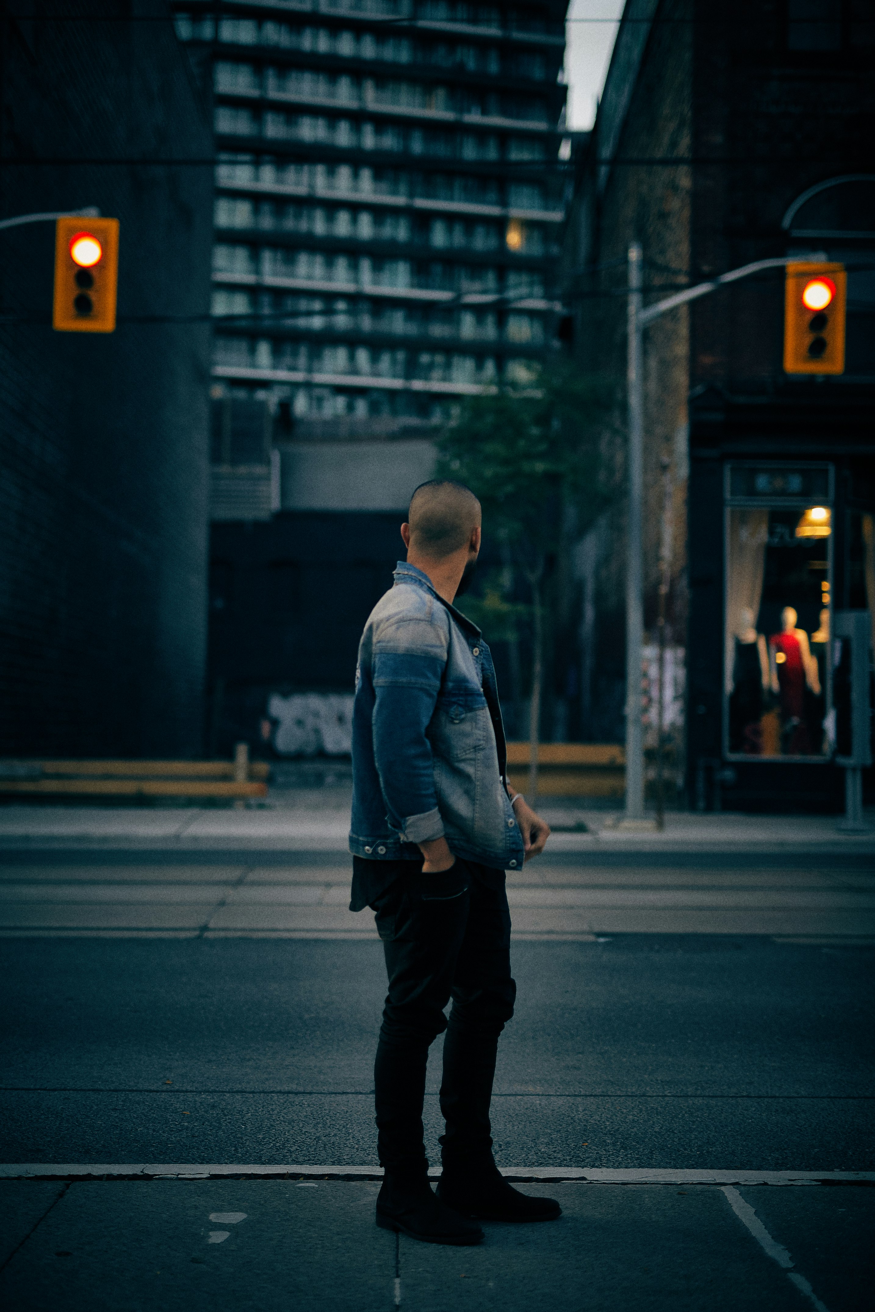 man standing near tall building and traffic lights